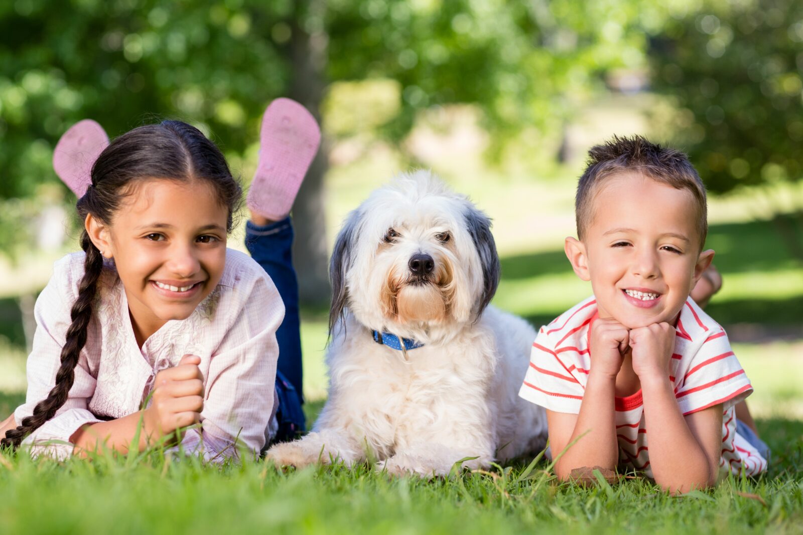 two children smiling with a dog